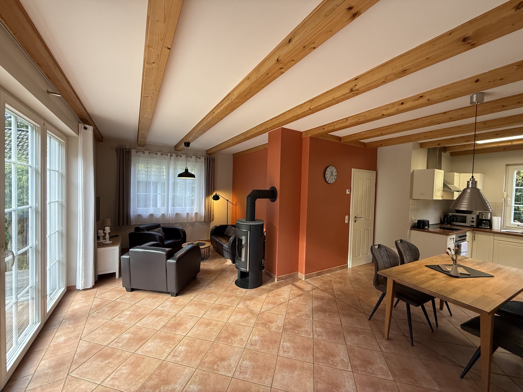 Living area with wood-burning stove, dining table and open kitchen in the holiday home