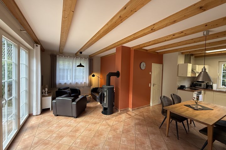 Living area with wood-burning stove, dining table and open kitchen